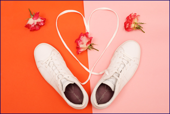 Pair of white sneakers with their laces in a heart shape 